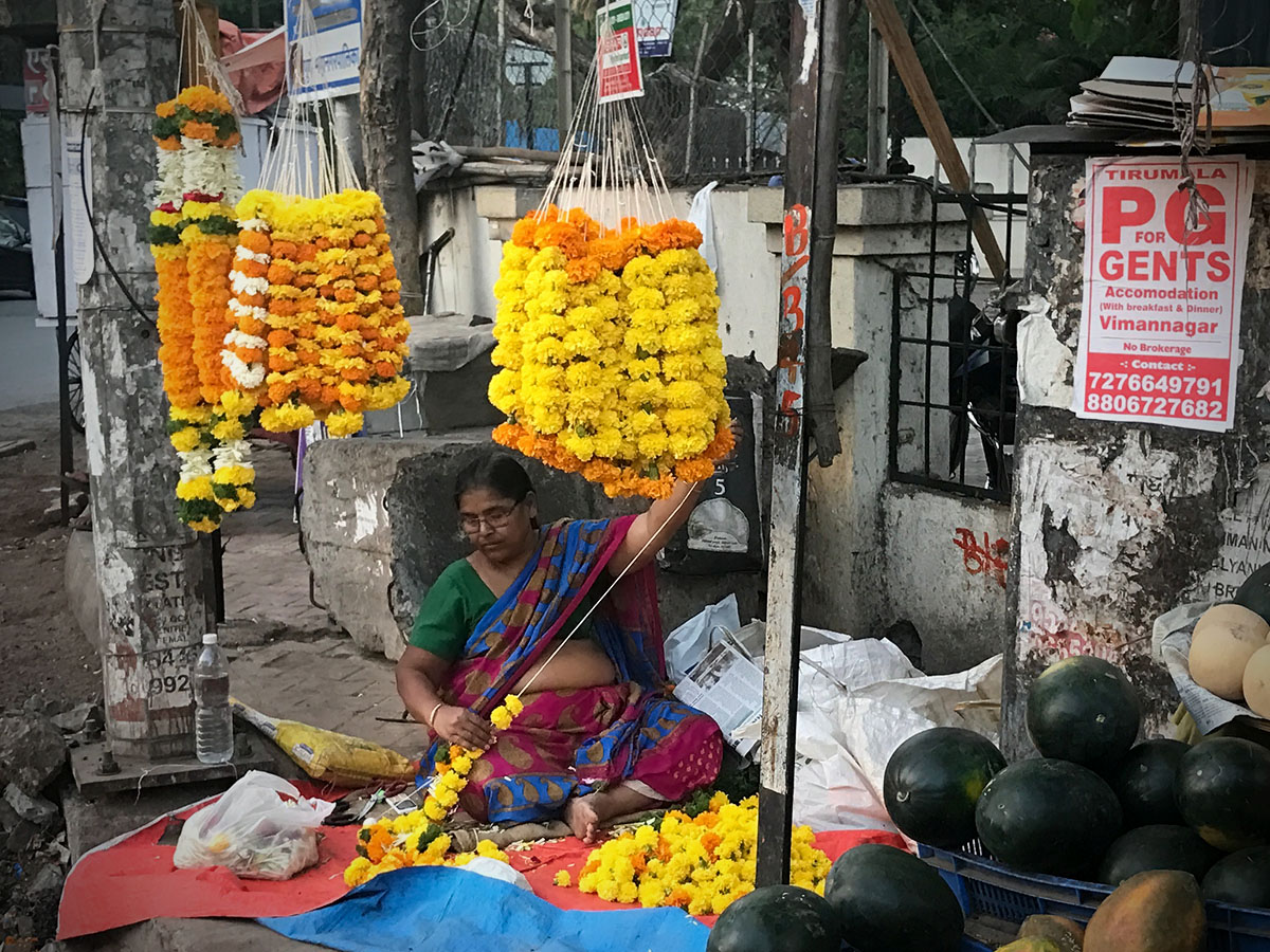 A lady marking garlands on the streets of Pune, India